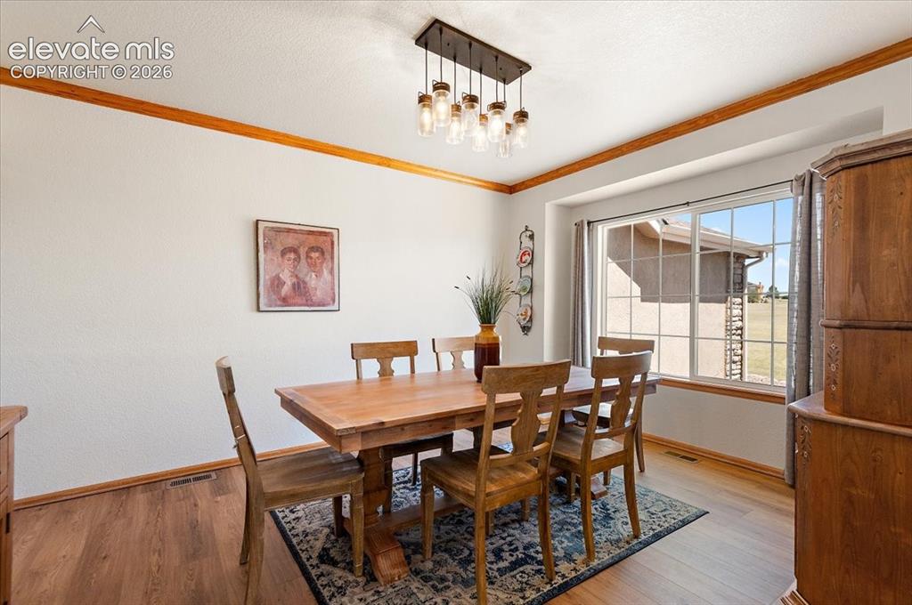 Image 6 of 47: Dining area featuring wood-finish flooring, a large window with grid panes,