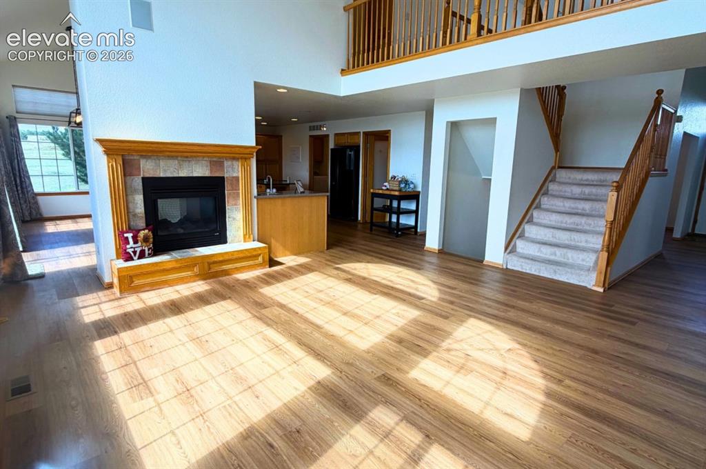 Image 6 of 48: Wood-finish flooring throughout, fireplace with tile surround, wood mantel,