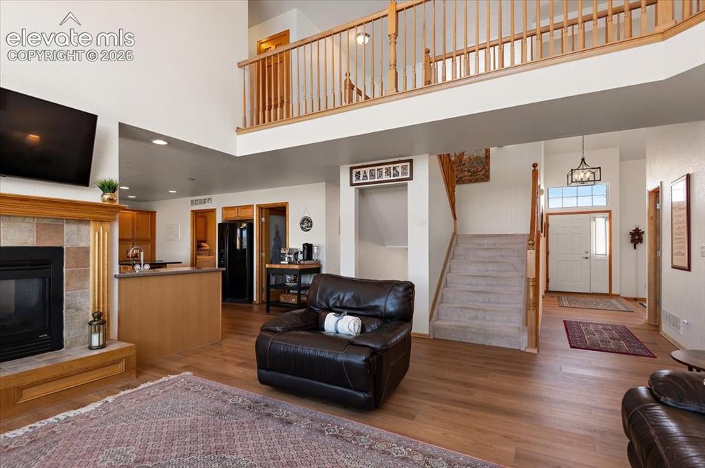 Image 7 of 47: Two-story living area featuring wood-finish flooring, a tile-surround firep
