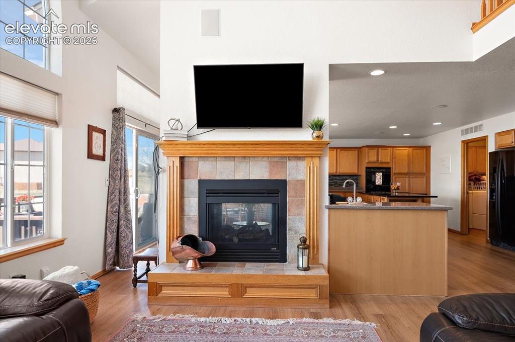 Image 8 of 47: Central fireplace featuring a wood mantel, tile surround, and a raised hear