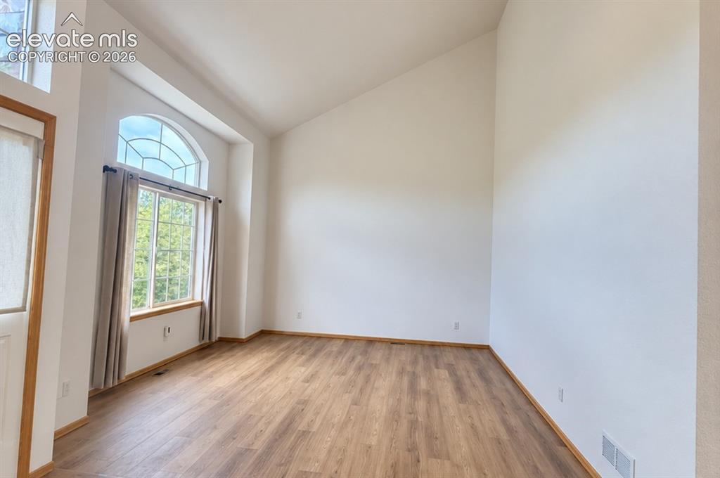 Image 9 of 48: Entry flex room. Vaulted ceiling, arched transom window, wood-finish floori