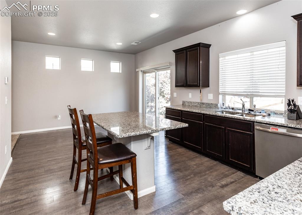 Image 13 of 40: Kitchen with stainless steel dishwasher, a breakfast bar area, dark wood-ty