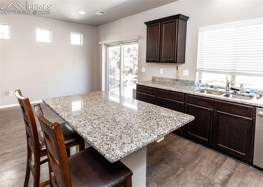 Image 14 of 40: Kitchen with dark wood finished floors, a kitchen bar, plenty of natural li