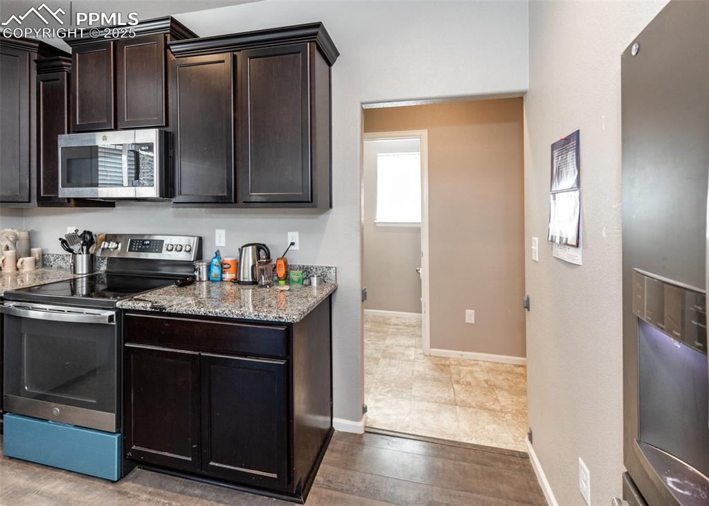 Image 16 of 40: Kitchen featuring appliances with stainless steel finishes, light stone cou