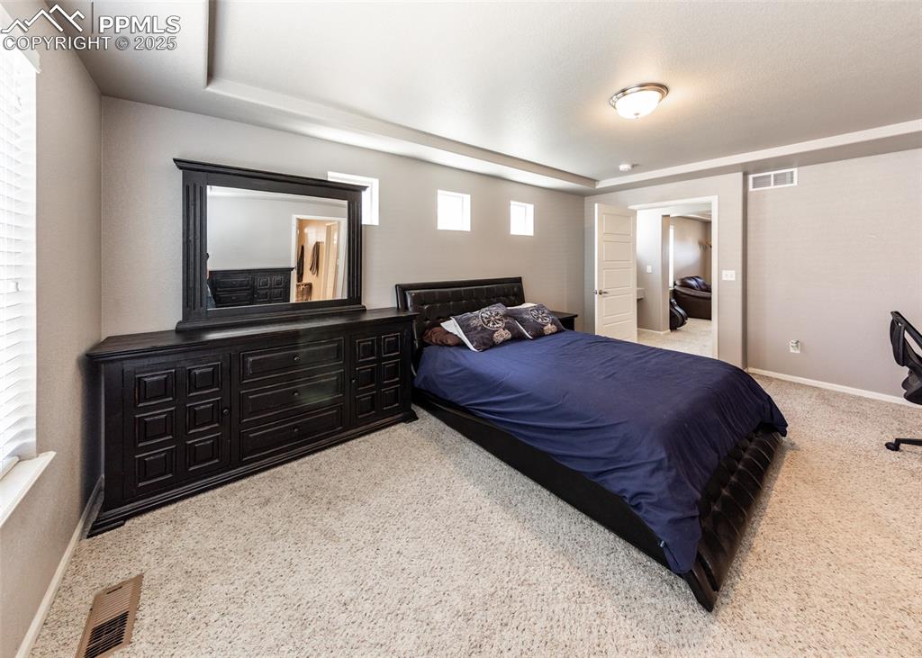 Image 28 of 40: Carpeted bedroom with a tray ceiling