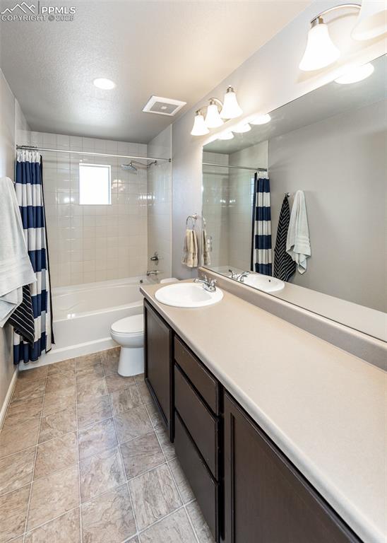 Image 33 of 40: Bathroom with vanity, shower / tub combo with curtain, and a textured ceili