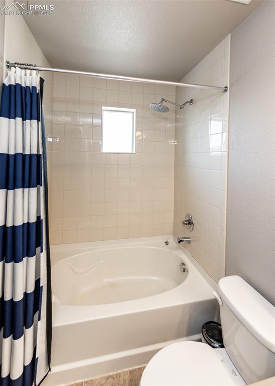 Image 34 of 40: Full bathroom featuring shower / bath combo with shower curtain and a textu