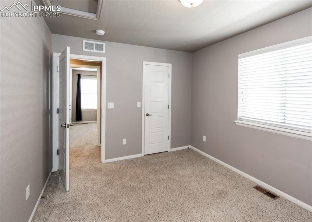 Image 36 of 40: Unfurnished bedroom featuring carpet and attic access