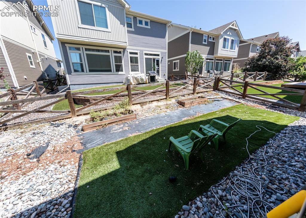Image 38 of 40: Back of house featuring a vegetable garden, a fenced backyard, and a reside
