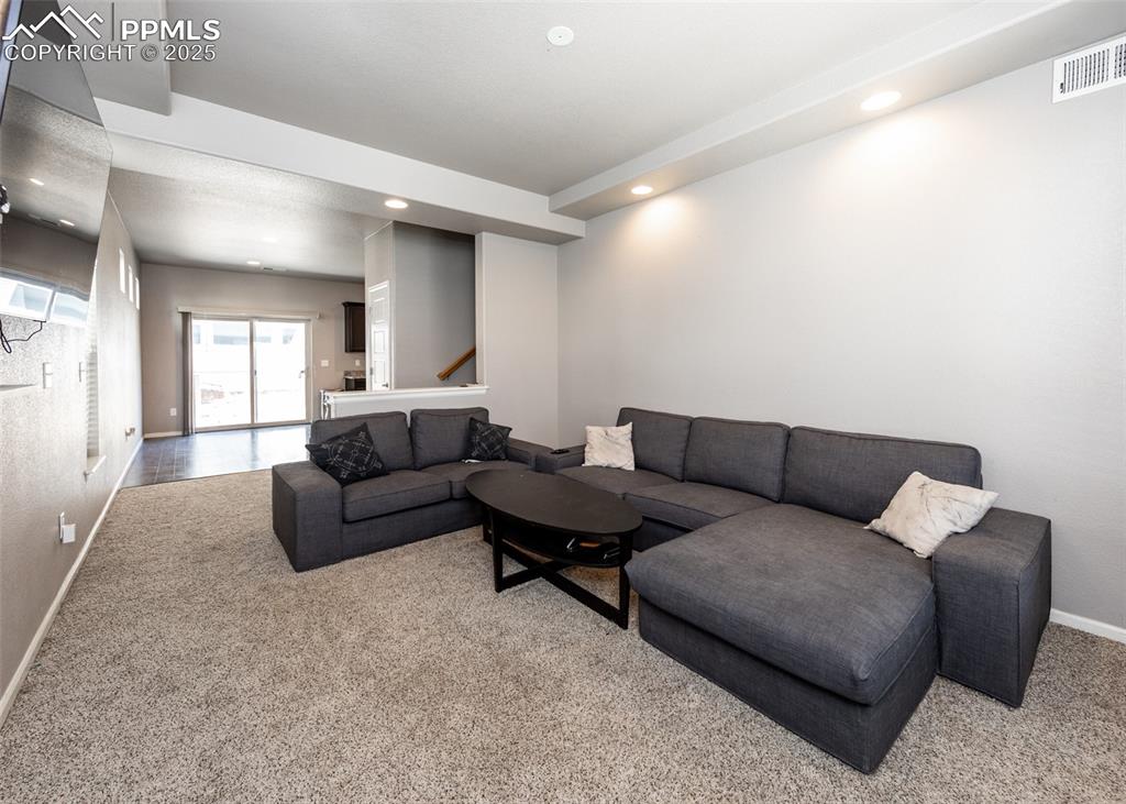 Image 4 of 40: Living area featuring light carpet, stairway, and recessed lighting