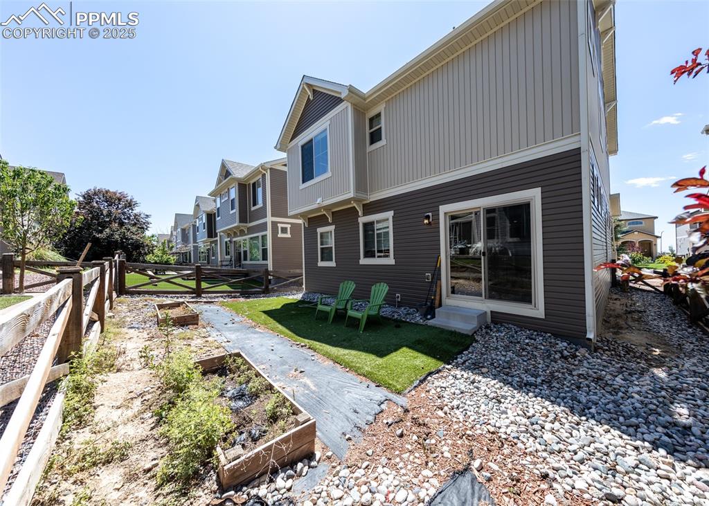 Image 40 of 40: Back of house featuring a vegetable garden and a residential view