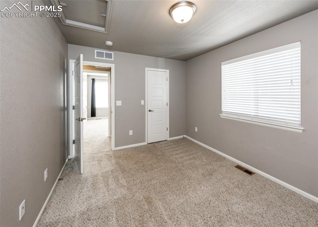 Image 43 of 50: Unfurnished bedroom featuring light carpet and attic access