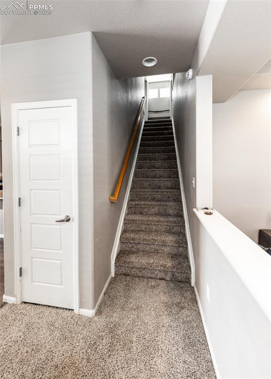 Image 8 of 40: Stairs with carpet floors and a textured ceiling