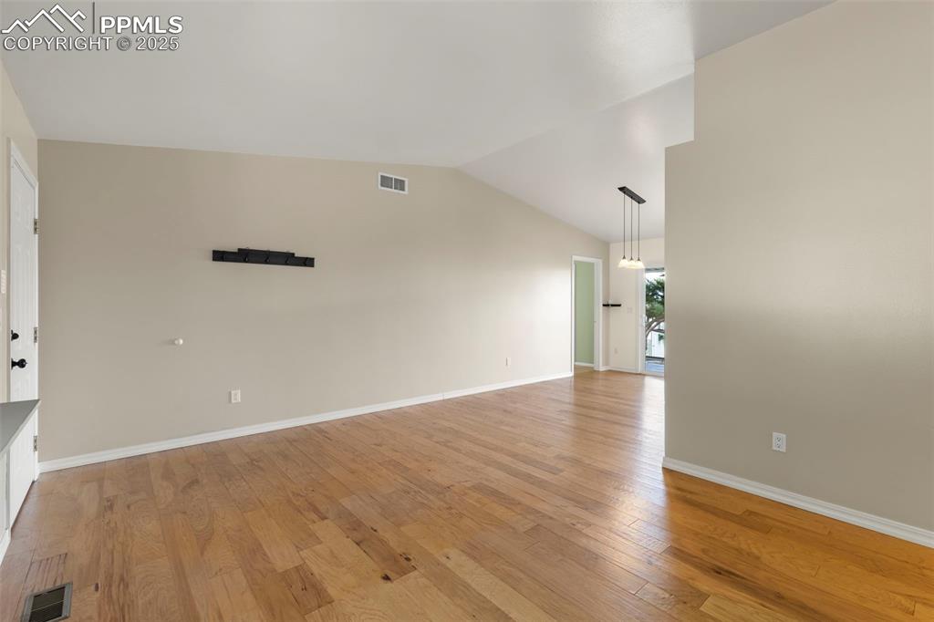 Image 3 of 27: Unfurnished room featuring vaulted ceiling and light wood finished floors