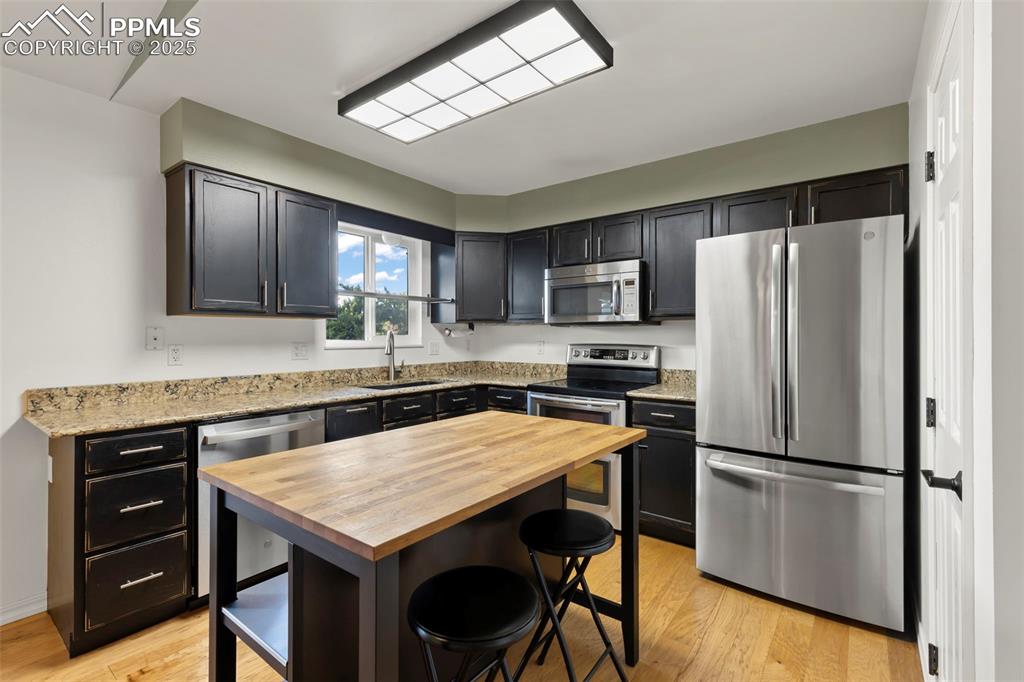 Image 5 of 27: Kitchen with stainless steel appliances, butcher block countertops, light w