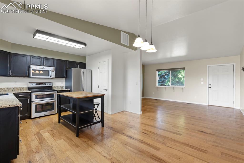 Image 6 of 27: Kitchen with stainless steel appliances, butcher block counters, open shelv