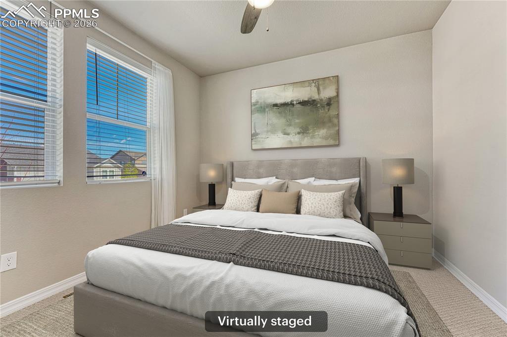 Image 22 of 42: This bedroom features two windows with blinds, a ceiling fan, and carpeted 