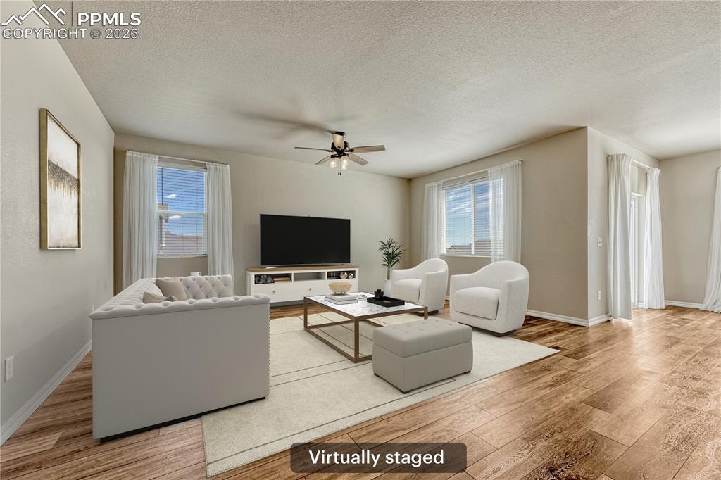 Image 3 of 42: The living room features hardwood flooring, a ceiling fan, and windows prov