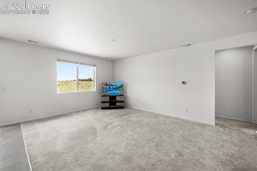 Image 18 of 25: Unfurnished room with light colored carpet and a smoke detector