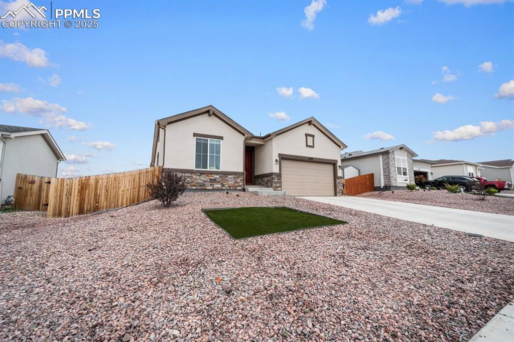Image 2 of 25: Ranch-style home with stone siding, stucco siding, driveway, and an attache