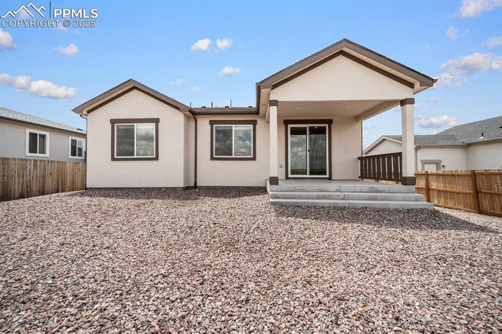 Image 21 of 25: Rear view of house with a fenced backyard, stucco siding, and a porch