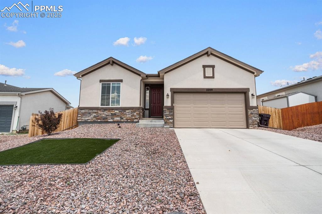 Image 3 of 25: Ranch-style house featuring stone siding, stucco siding, driveway, and a ga
