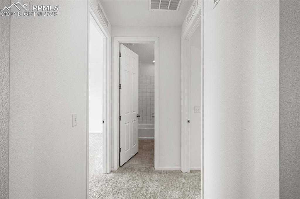 Image 5 of 25: Corridor featuring light carpet and baseboards