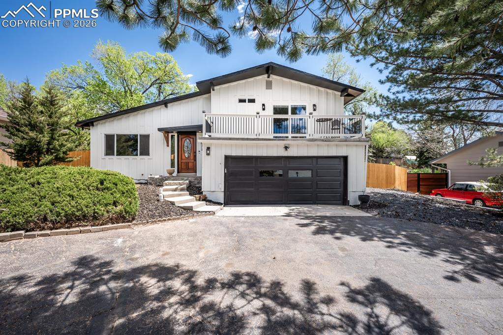 Caption: View of front of house featuring board and batten siding, driveway, a garage, and a balcony