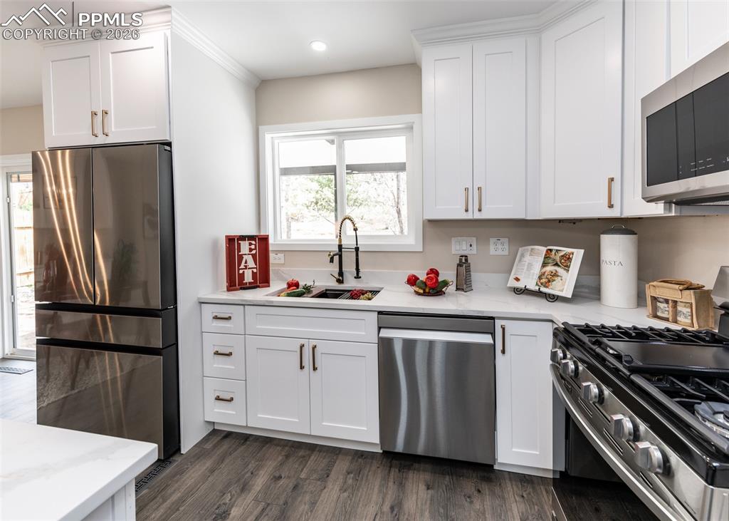 Image 11 of 48: Kitchen featuring appliances with stainless steel finishes, white cabinets,