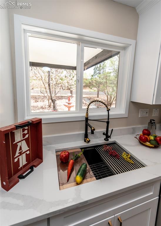 Image 12 of 48: Kitchen view of light stone counters and white cabinetry