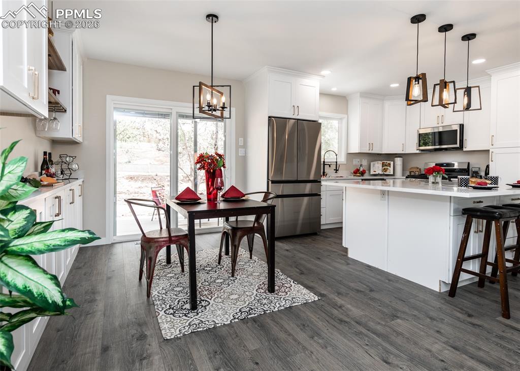 Image 15 of 48: Kitchen with stainless steel appliances, white cabinetry, pendant lighting,