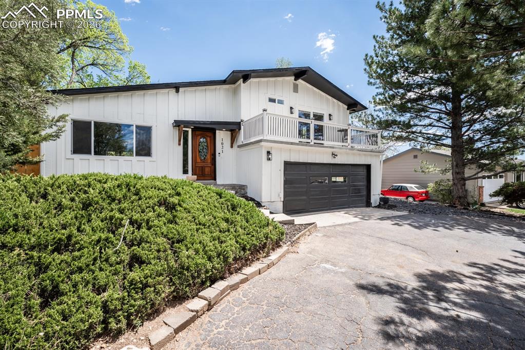 Image 2 of 48: Modern farmhouse with board and batten siding, driveway, an attached garage
