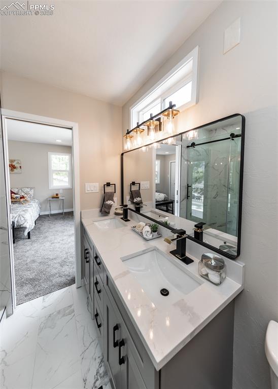 Image 25 of 48: Ensuite bathroom with double vanity, light marble finish floors, and a marb