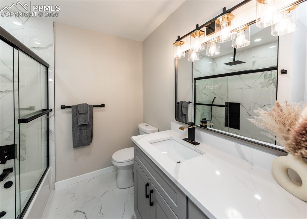 Image 29 of 48: Full bathroom with light marble finish floors, vanity, and a combined bath 