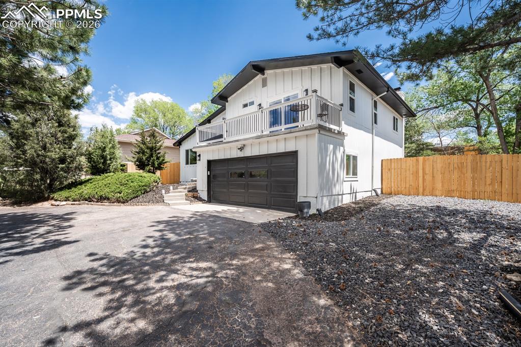 Image 3 of 48: View of side of home with driveway, board and batten siding, a balcony, and
