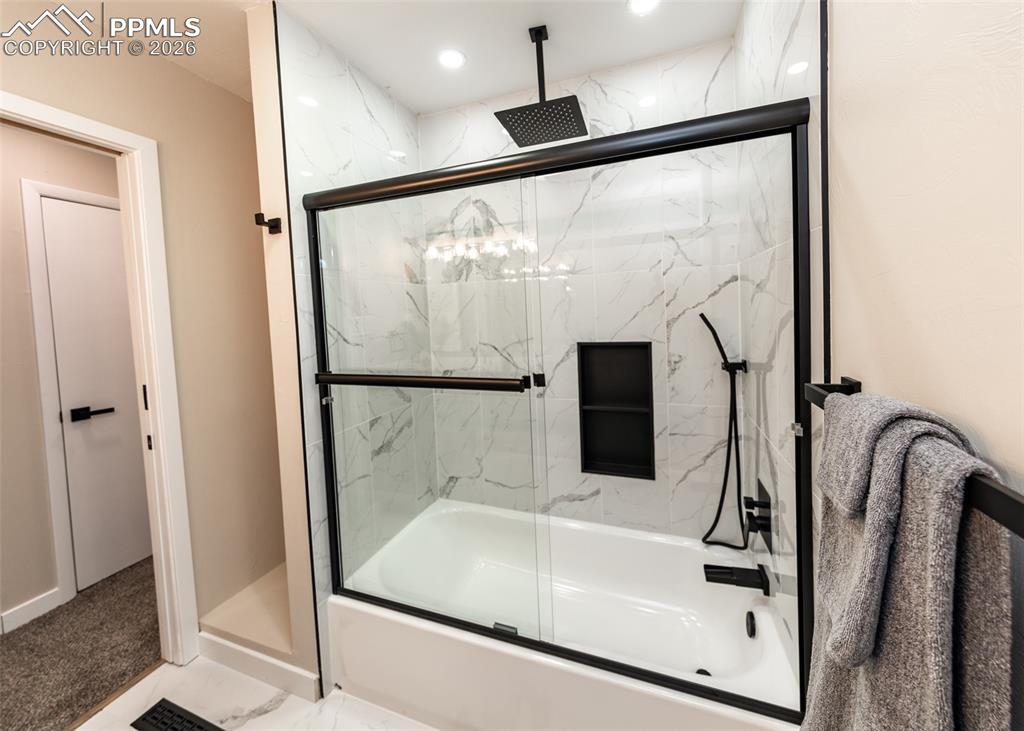 Image 31 of 48: Full bath with a combined bath / shower with rainfall shower, marble look t