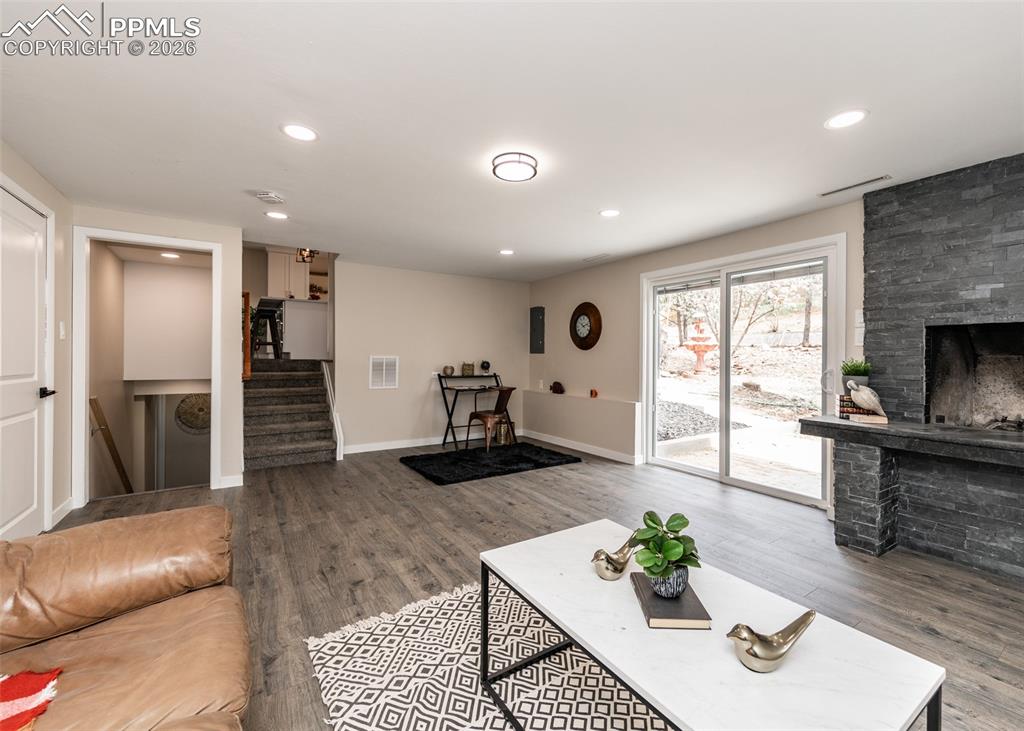 Image 33 of 48: Living room with a fireplace, wood finished floors, stairs, and recessed li