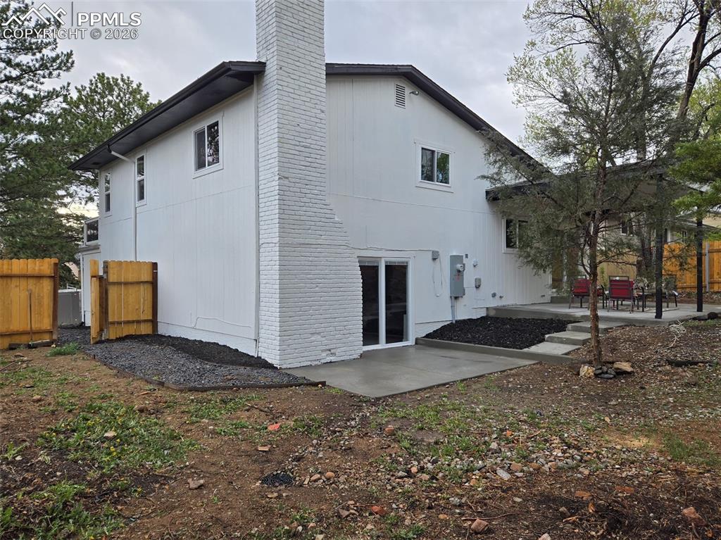 Image 43 of 48: Back of property featuring a patio area, a chimney, and brick siding