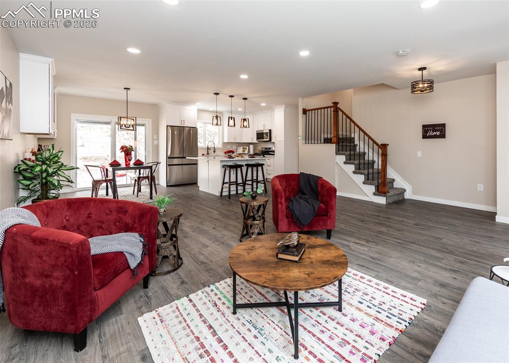 Image 7 of 48: Living area featuring recessed lighting, stairs, and dark wood-style floors