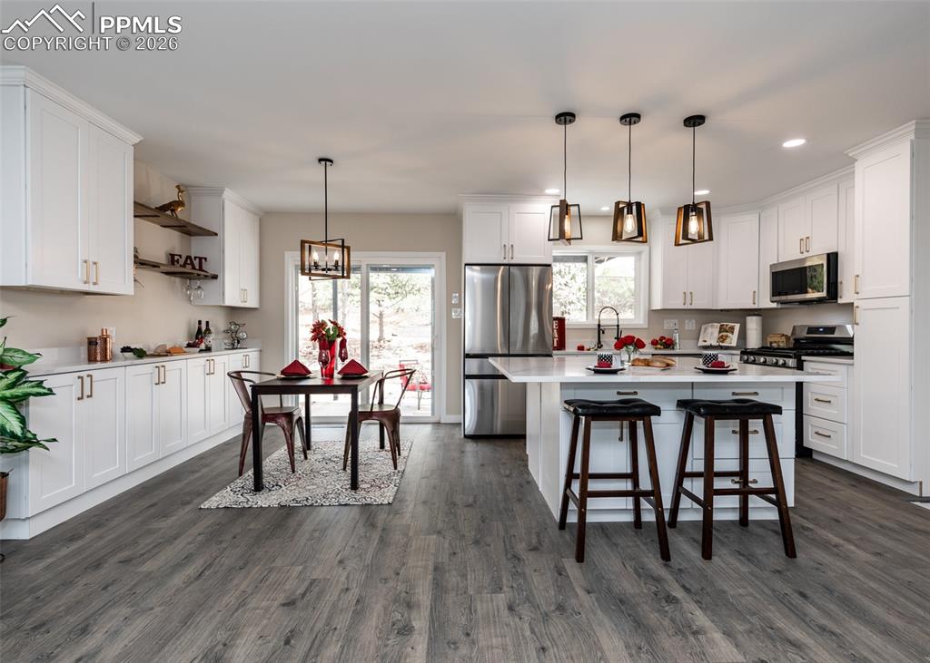 Image 9 of 48: Kitchen featuring stainless steel appliances, white cabinets, pendant light
