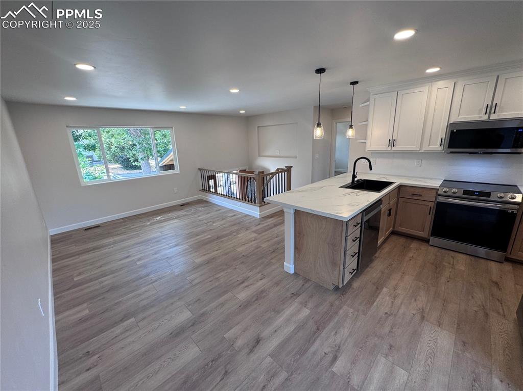 Image 12 of 36: Kitchen with stainless steel appliances, white cabinetry, recessed lighting
