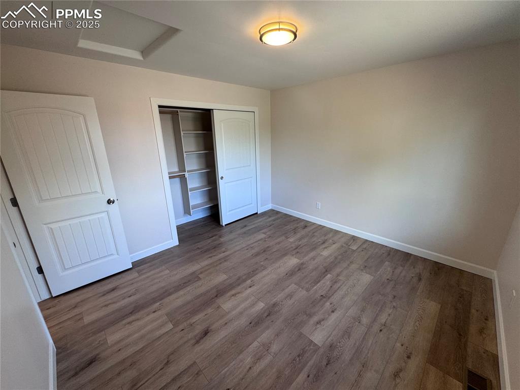 Image 18 of 36: Unfurnished bedroom with attic access, wood finished floors, and a closet