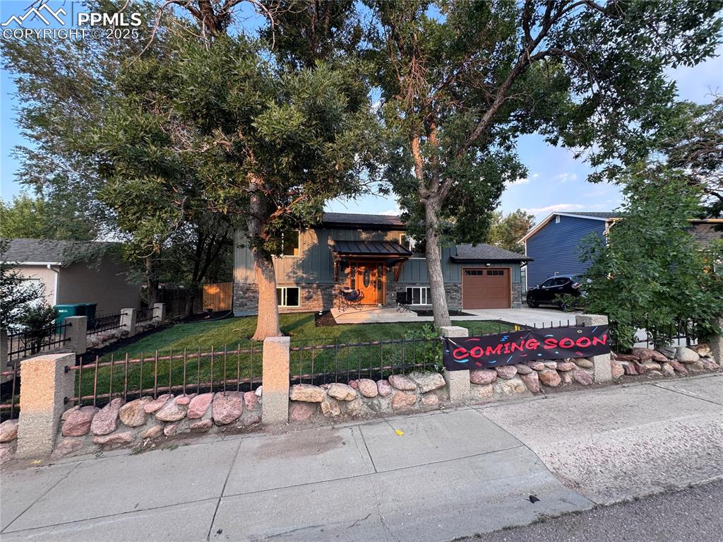 Image 2 of 36: View of front of home featuring driveway, a fenced front yard, and board an
