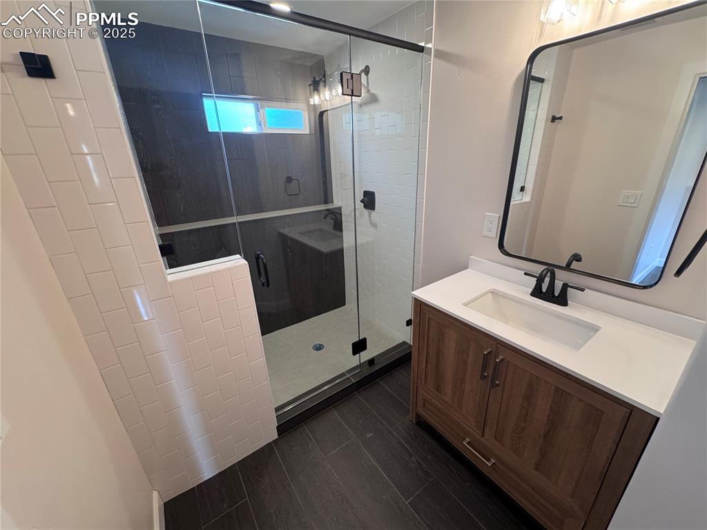Image 32 of 36: Bathroom with vanity, a shower stall, and dark wood finished floors