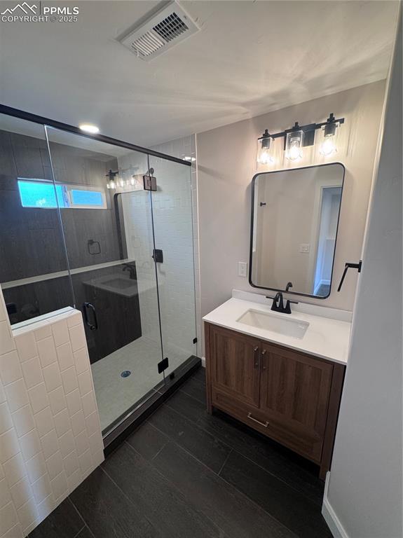 Image 34 of 36: Bathroom with vanity, a shower stall, and dark wood-style flooring