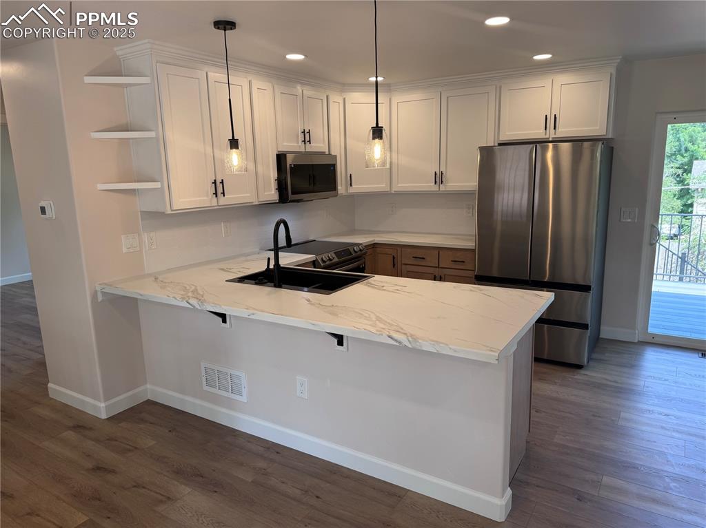 Image 5 of 36: Kitchen featuring stainless steel appliances, pendant lighting, dark wood-t