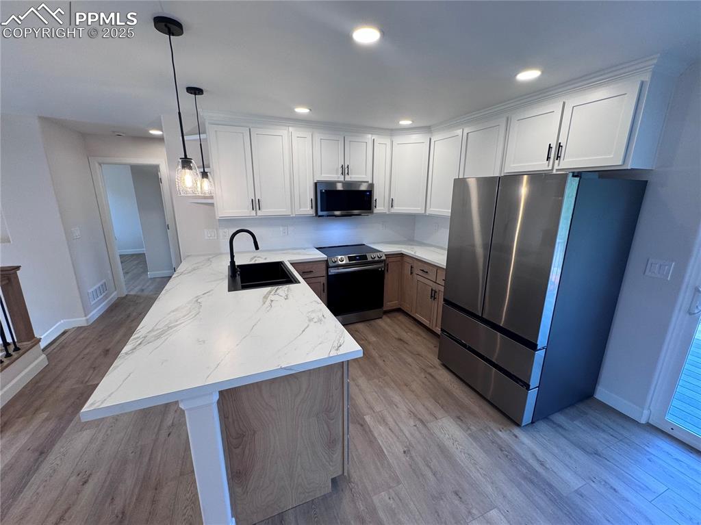 Image 9 of 36: Kitchen with a peninsula, stainless steel appliances, recessed lighting, wh