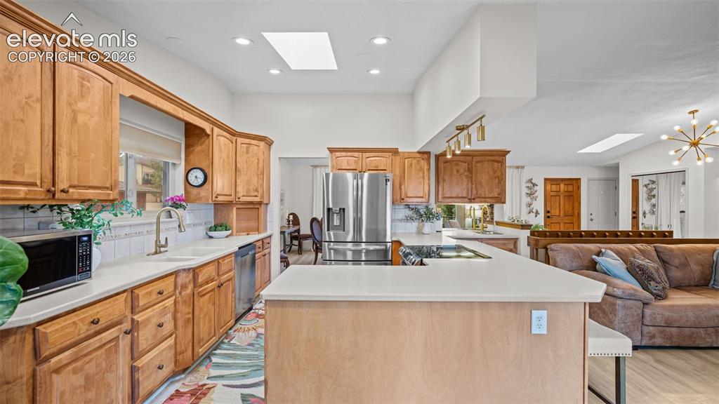 Image 20 of 50: Kitchen featuring honey-toned wood cabinetry, light countertops, and a whit