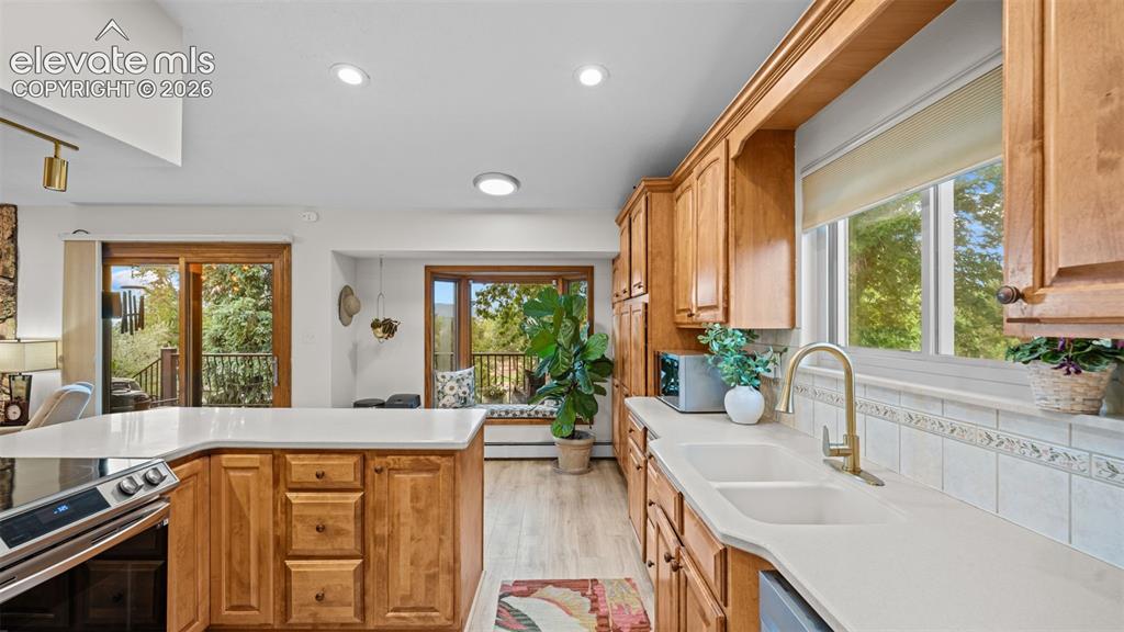 Image 23 of 50: Kitchen featuring a large island with white countertops, light wood-finish 
