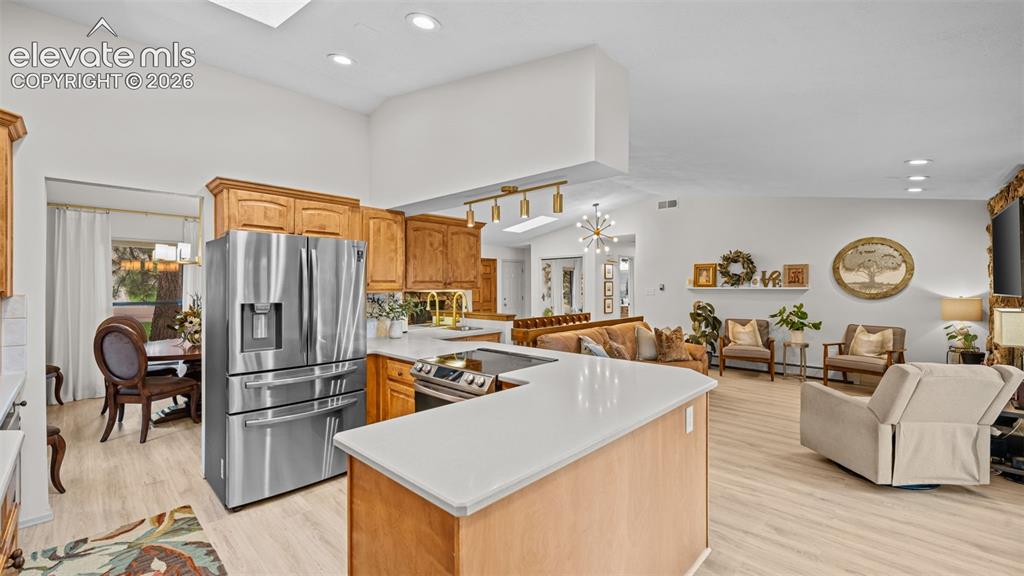 Image 25 of 50: Open-concept living space featuring a kitchen with wood cabinetry, stainles